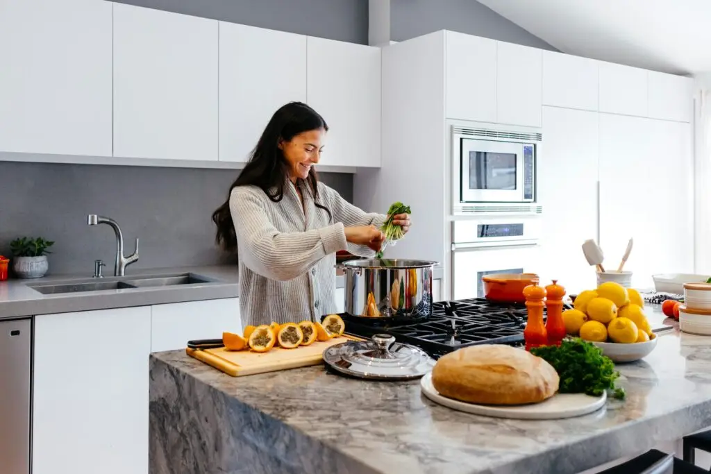 In a vibrant kitchen, a woman prepares a variety of foods aimed at supporting hormone balance and heart wellness.